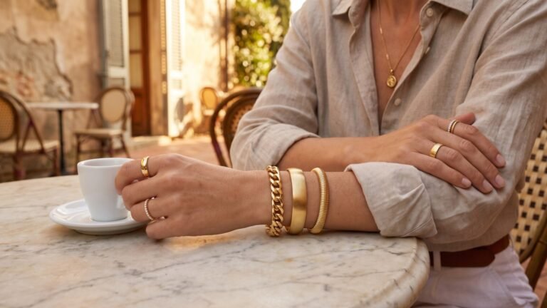 Woman wearing stacked Italian gold bracelets and rings while enjoying espresso at an outdoor cafe